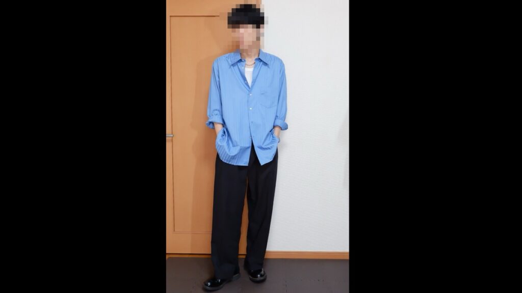 青のシャツを白のタンクトップの上に真ん中だけ留めて着て、袖をまくり、黒のワイドスラックスと黒の革靴を合わせたコーデ