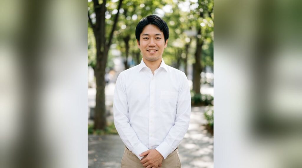 明るい並木道で白いシャツにベージュのパンツを着て笑う男性のプロフィール写真
